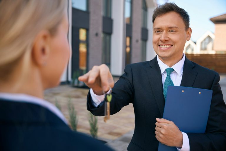 Cheerful estate agent giving keys to female client